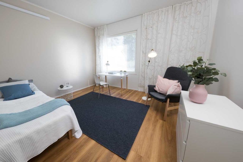 Yksikössä sijaitseva huone, sisustettu vaaleilla väreillä ja huonekaluilla