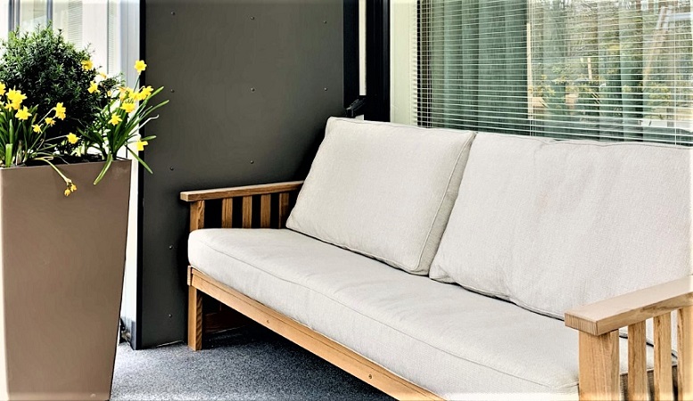 Onnikoti Jokipuiston terassi, jossa valkoinen sohva ja kukka-asetema