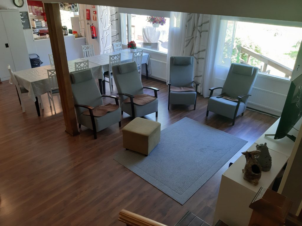 Onnikoti Kertun olohuone, jossa neljä nojatuolia, televisio ja ruokailuryhmä