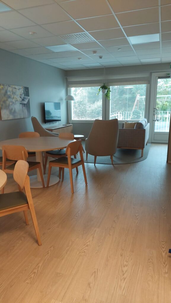 Onnikoti Apilan oleskelutila, jossa ruokailuryhmä, kaksi nojatuolia, sohva ja televisio.