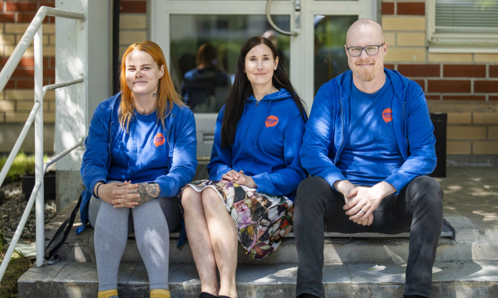 Kolme Onnikotien työntekijää istuu ulkorappusilla.