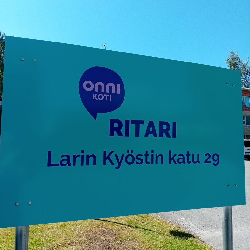 Onnikoti Ritarin kyltti, jossa  osoite ja Onnikotien logo: Larin Kyöstin katu 29