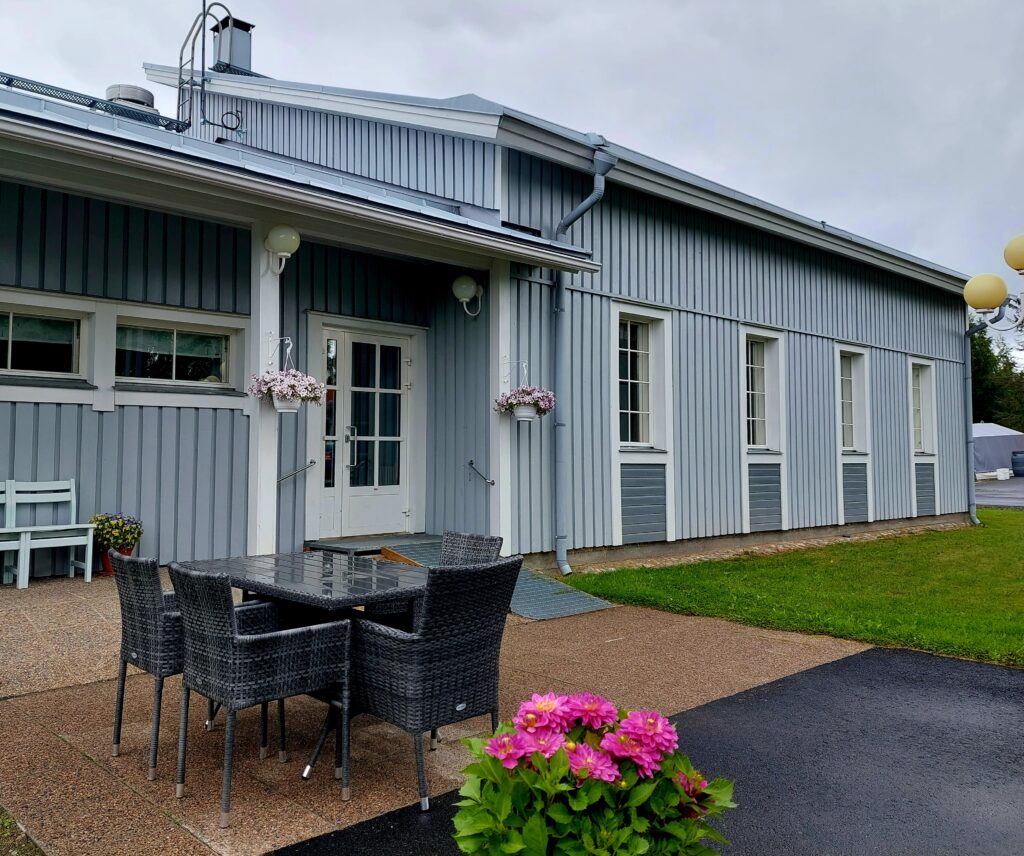 Onnikoti Poppelin sininen puinen rakennus ja edessä pihalla puutarhakalusteet