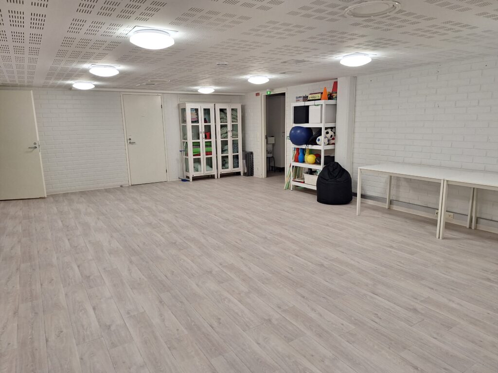 Vaalea iso huone, jossa hyllyköitä