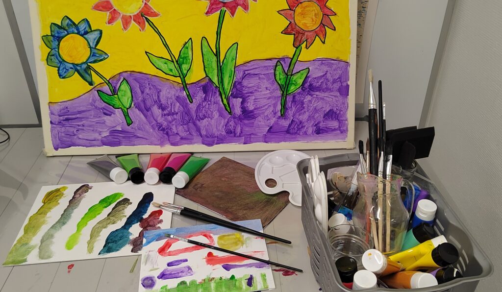 maalattu taulu ja maalaustarvikkeita.