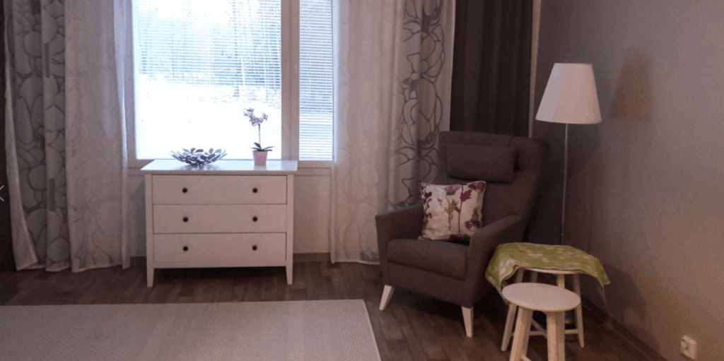 Onnikoti Kehrän huone, jossa on lipasto, nojatuoli ja kaksi pöytää.