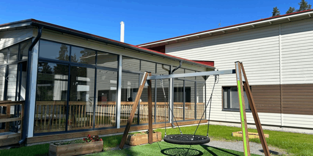 Onnikoti Valon rakennus ja piha, jossa nurmikko ja keinu.