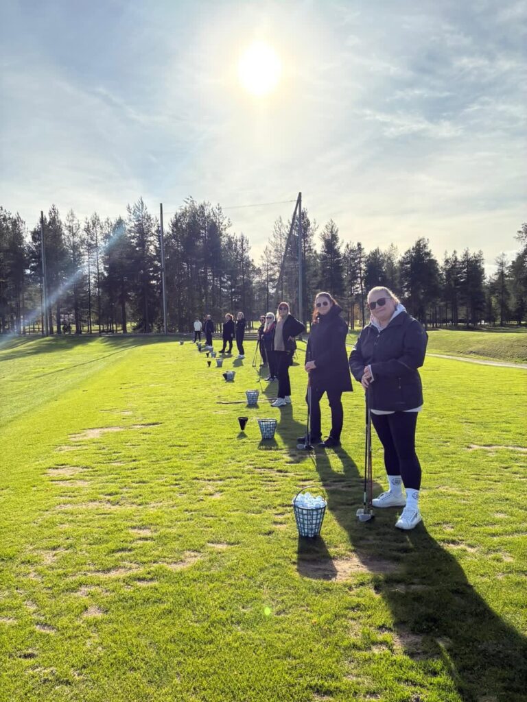 Henkilöitä rivissä aurinkoisessa säässä ulkona nurmikkokentällä.
