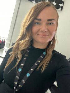 Yksikönjohtaja Jenni Kaneva hymyilee mustassa paidassa kaulassaan Onnikotien avainnauha