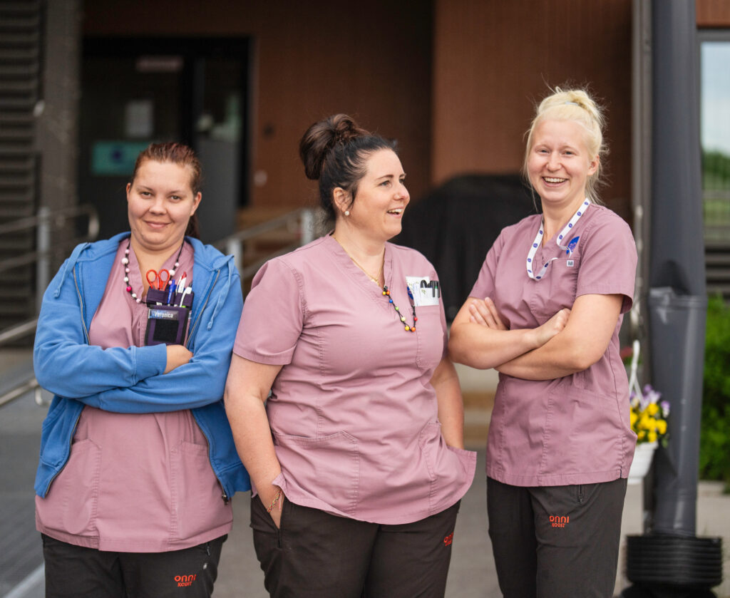 Kolme Onnikotien työntekijää seisoo ulkona asumisyksikön oven edessä.