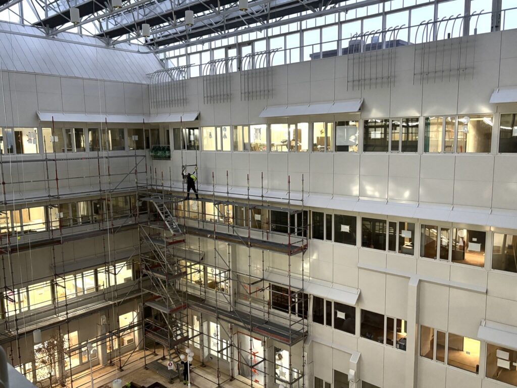 Onnikoti Katariinan työmaa rakennuksen atriumpihalta katsottuna, rakennustelineitä, ikkunoita, lasikatto