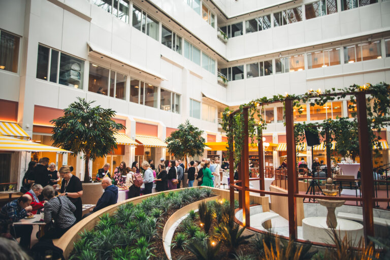 Vaalea atrium-piha, jossa viherkasveja ja avajaisvieraita.
